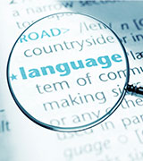 Magnifying glass over the word language in the dictionary, representing focal point of all Love of Language Certificate courses for K-12 educators