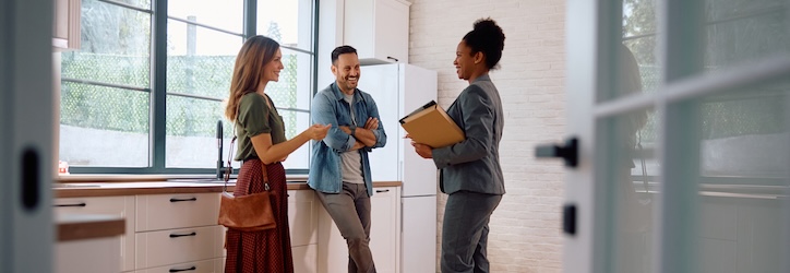 Three individuals engaged in conversation while standing in a modern kitchen.