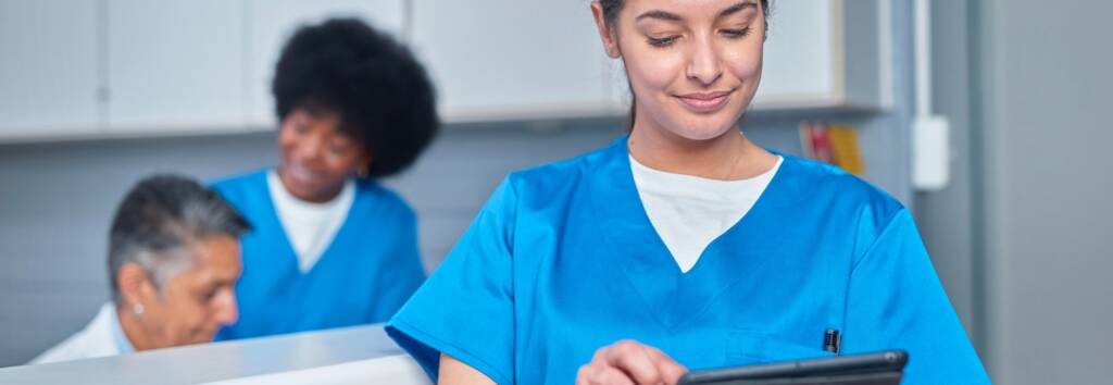 Healthcare professionals collaborate at the front desk area, utilizing technology such as tablets to enhance efficiency, portraying teamwork, modernization, and attentive patient care.