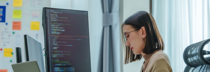 Asian prompt engineer develop coding app with software data sitting in front of computer monitor at office
