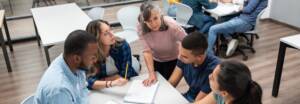 Teacher in class explaining something to a group of Latin American students at a community college - education concepts