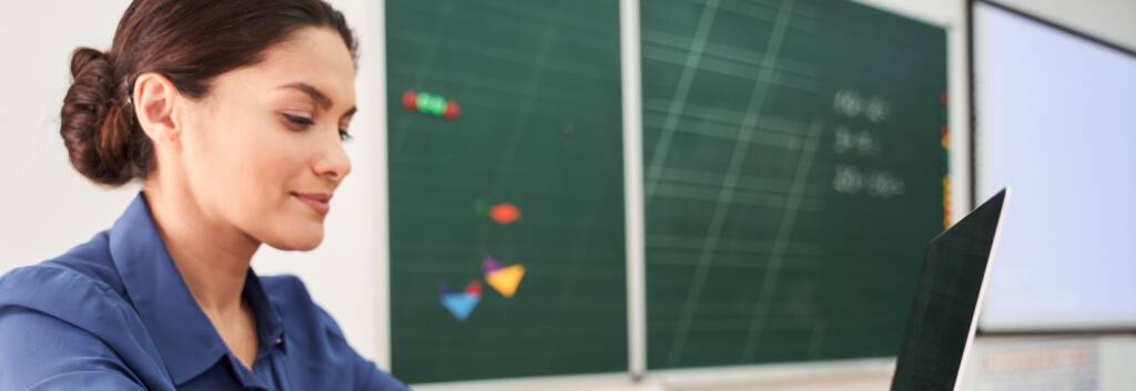 women sitting at a desk in a classroom using a laptop